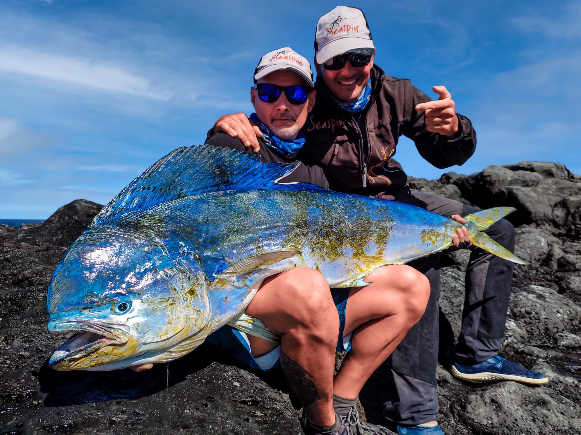 Zwei Angler mit einer großen Goldmakrele auf den schwarzen Lavafelsen der Küste von Lanzarote